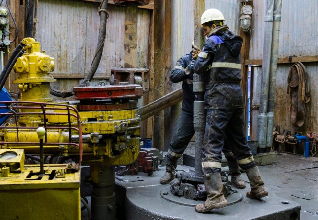 Offshore oil rig worker prepare tool and equipment for perforation oil and gas well at wellhead platform. Making up a drill pipe connection. A view for drill pipe connection from between the stands